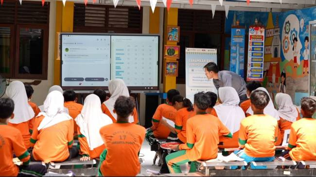 Guru dan siswa menggunakan papan digital interaktif selama kegiatan belajar di luar ruangan.