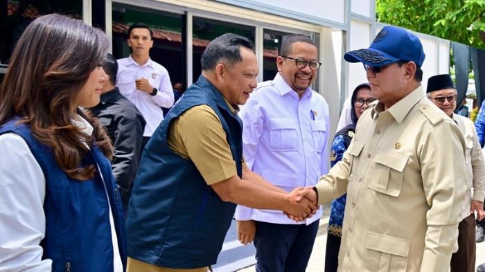 Foto Presiden Prabowo Subianto berjabat tangan dengan seorang pejabat daerah saat kunjungan resmi, didampingi Menteri Dalam Negeri Tito Karnavian dan beberapa tamu lainnya di luar sebuah gedung.