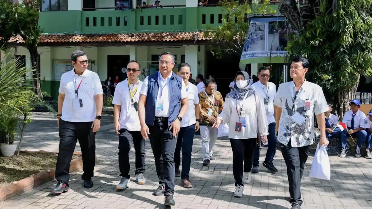 Rombongan pejabat dan perwakilan Telkom berjalan di halaman sekolah saat kunjungan terkait digitalisasi pembelajaran.